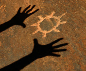 Shadow Of Hands Worshipping Sun Petroglyph Carved Into Sandstone